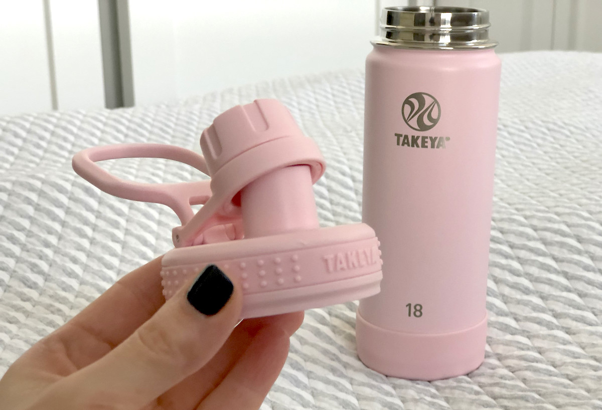 hand holding pink lid with takeya water bottle in background