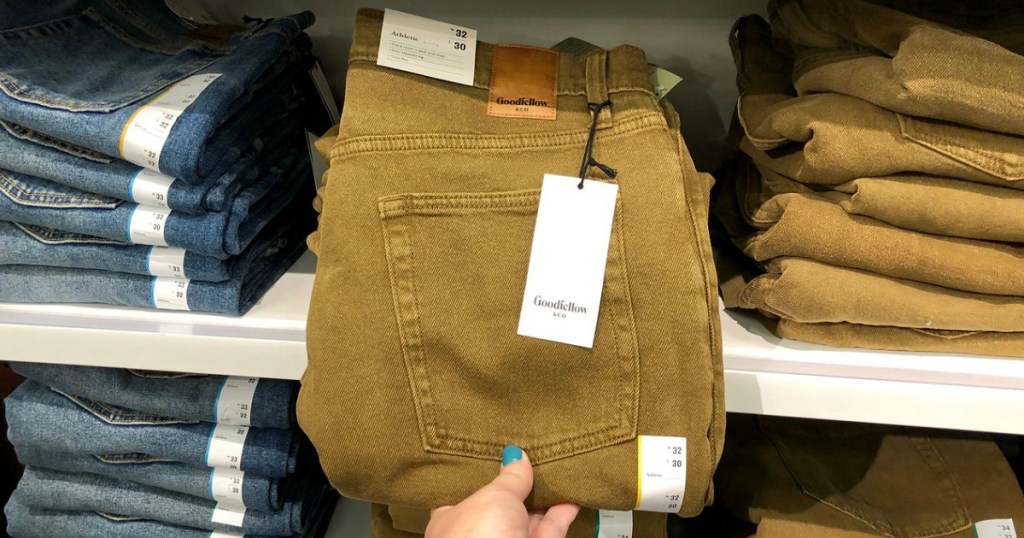 hand holding a pair of jeans in a store