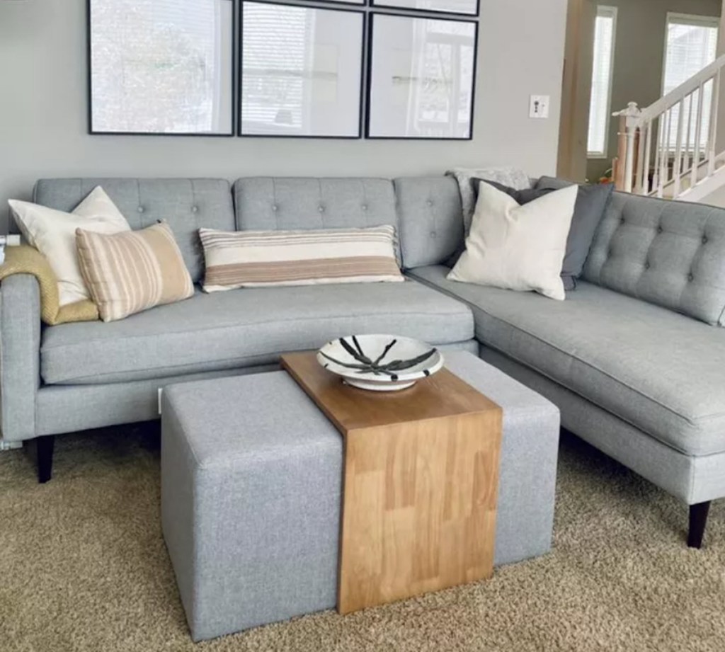 living room with gray sectional couch and waterfall coffee table with pillows and various decor