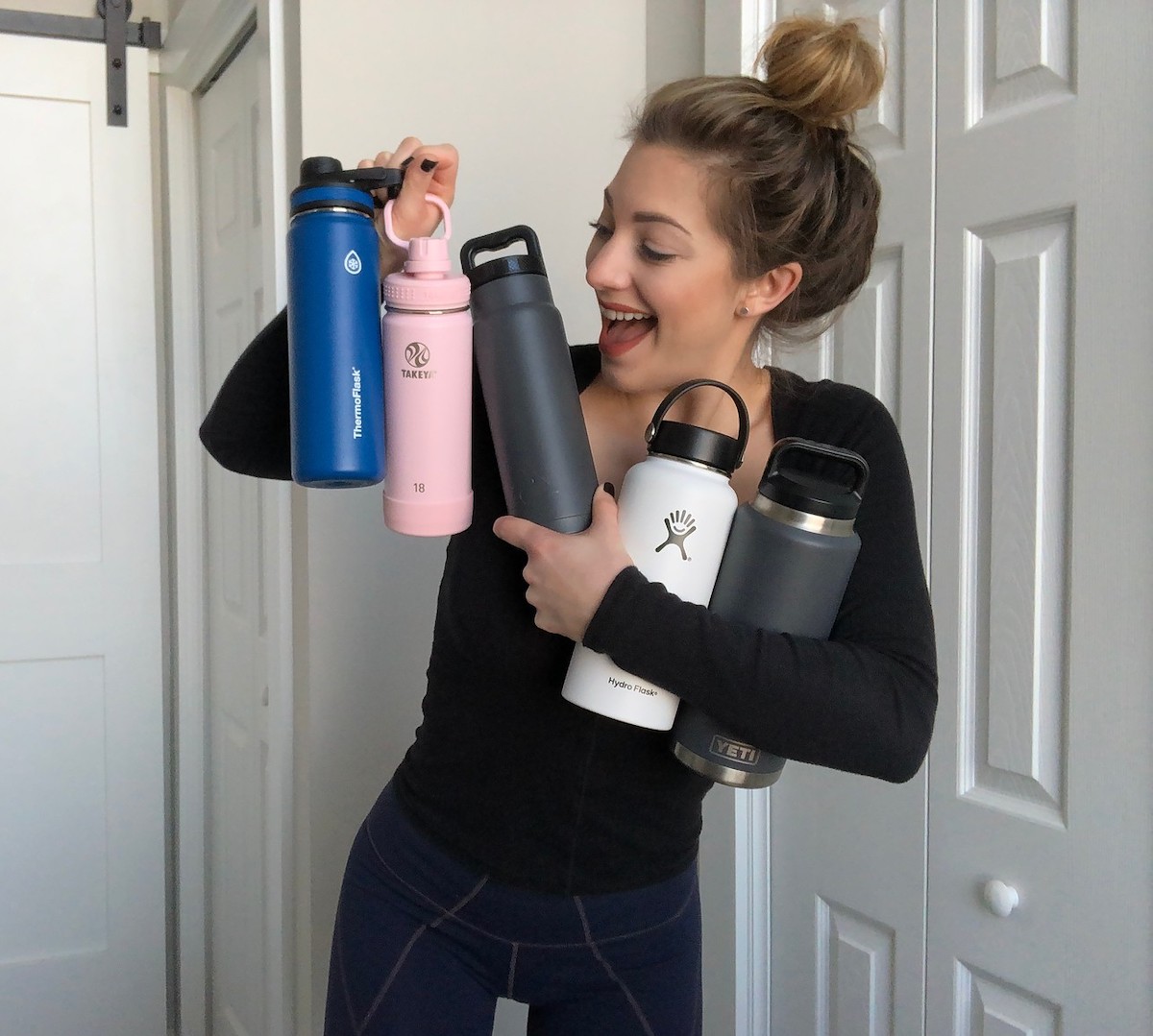 woman holding various styles of water bottles 
