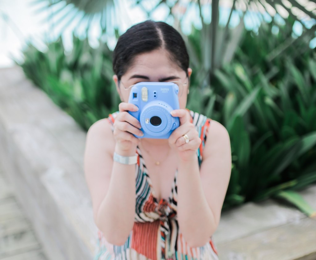 woman holding blue instax film camera wedding ideas on a budget