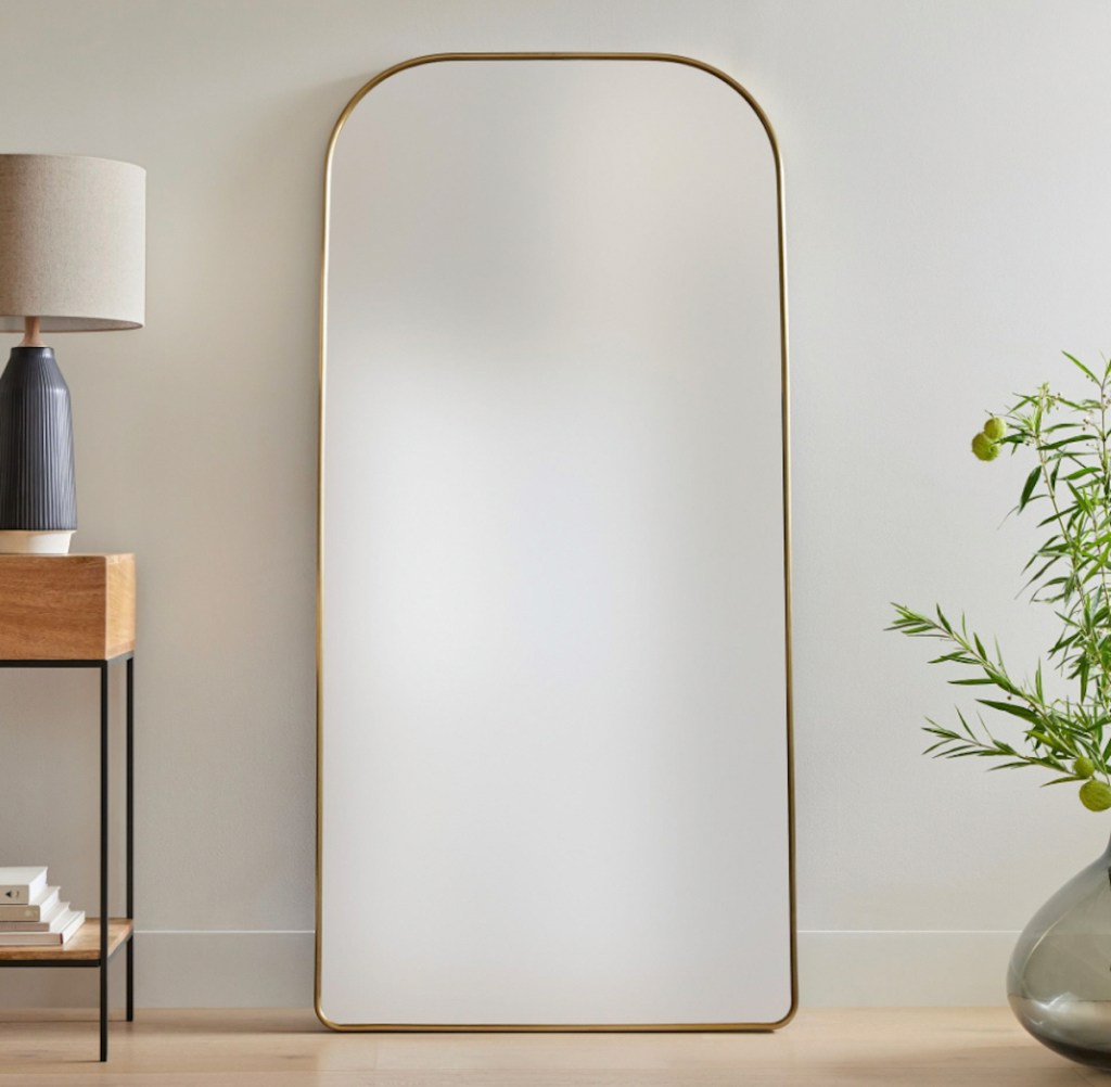 gold floor mirror leaning on wall