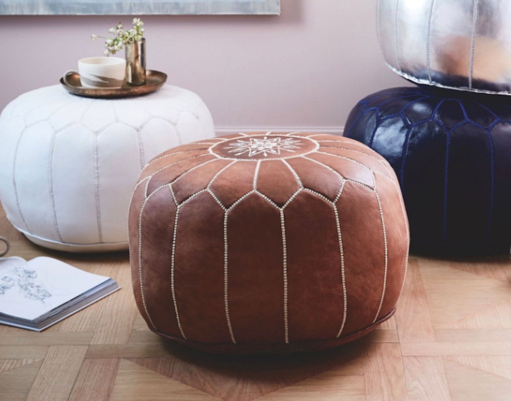 brown leather moroccan leather pouf with other poufs stacked in background
