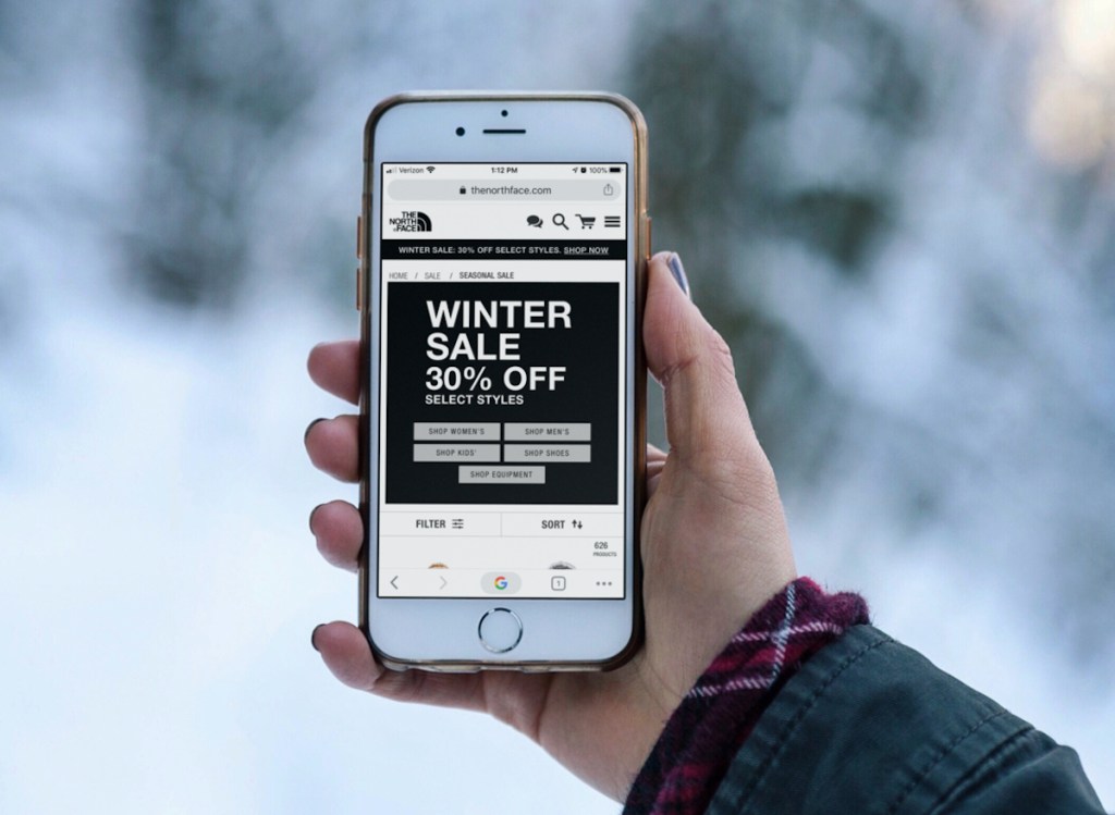 hand holding cell phone with winter sale on screen
