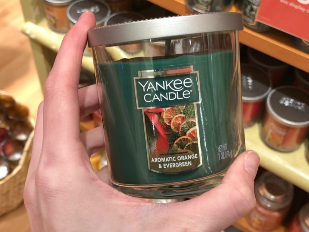 hand holding green candle by store display