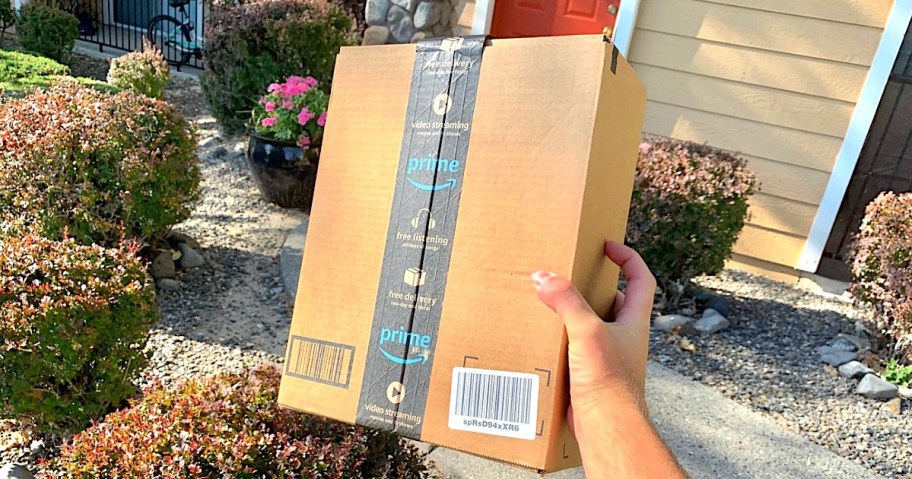 Amazon Prime box in hand in front of house