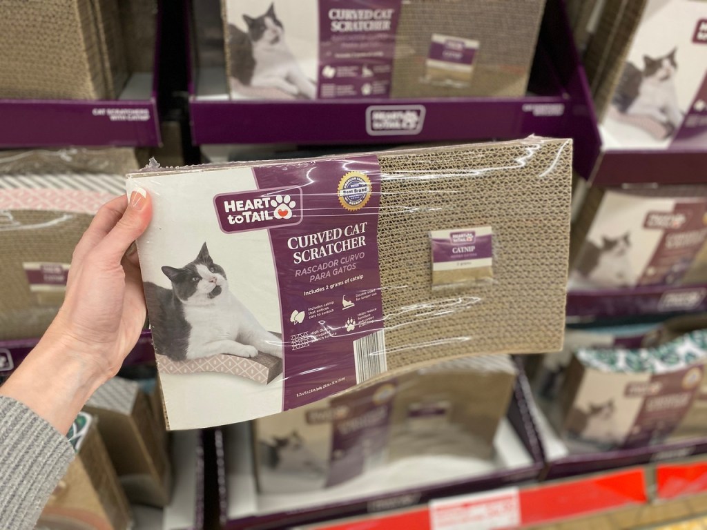 woman's hand holding up a curved cat scratcher in the package at the store