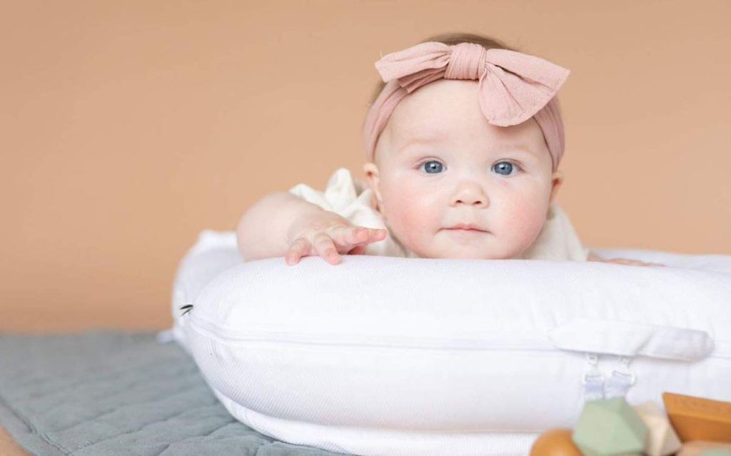 baby sitting on white bed looking at the camera