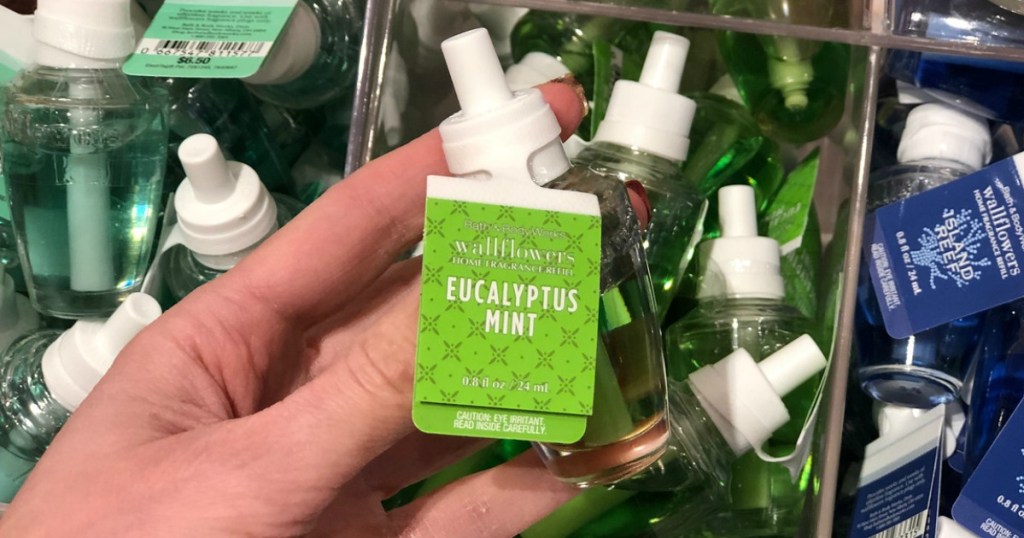 Small green scent refill for wall plug in, in hand near in-store display