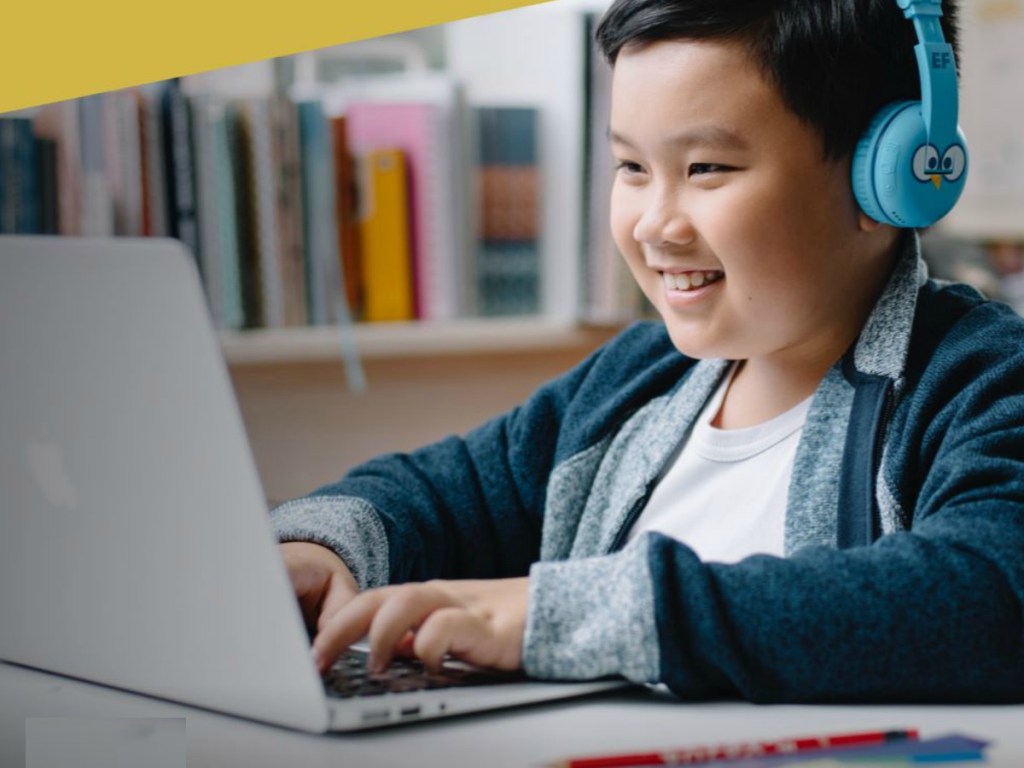 Boy wearing blue headphones and working on computer
