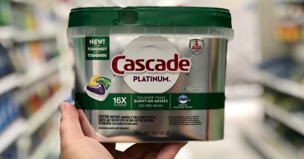 package of dishwasher detergent being held up in the aisle of a store