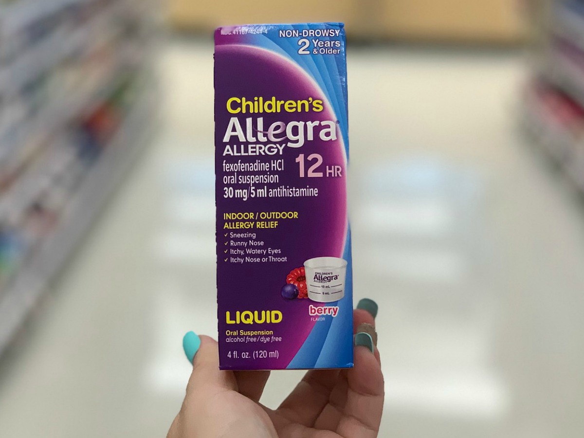 Woman's hand holding a box of children's allergy medicine