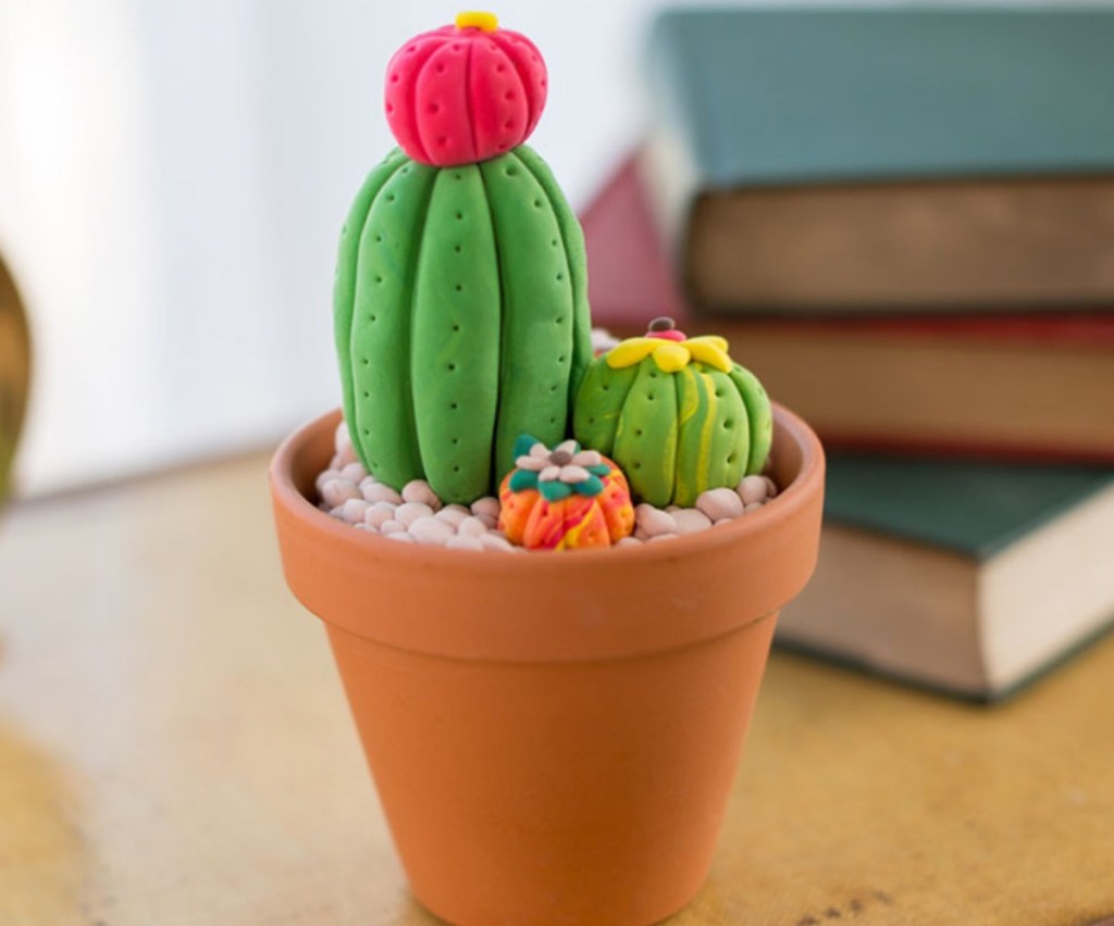 succulents made of clay in terracotta pot near stack of books