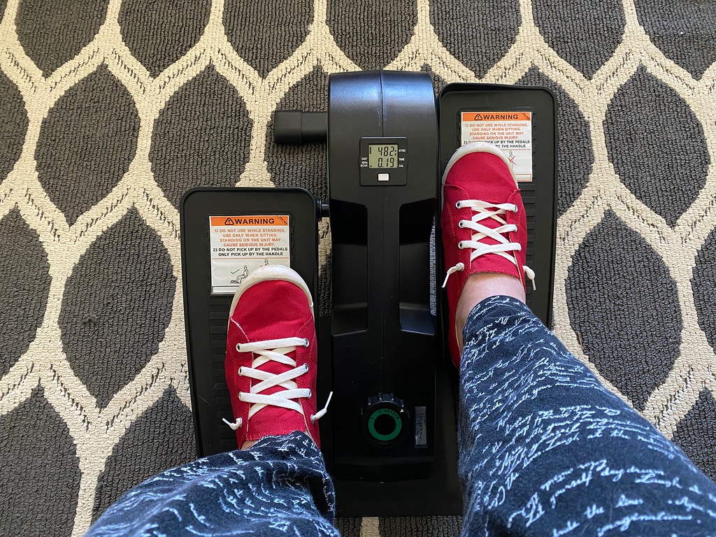 person wearing red shoes using an under desk elliptical