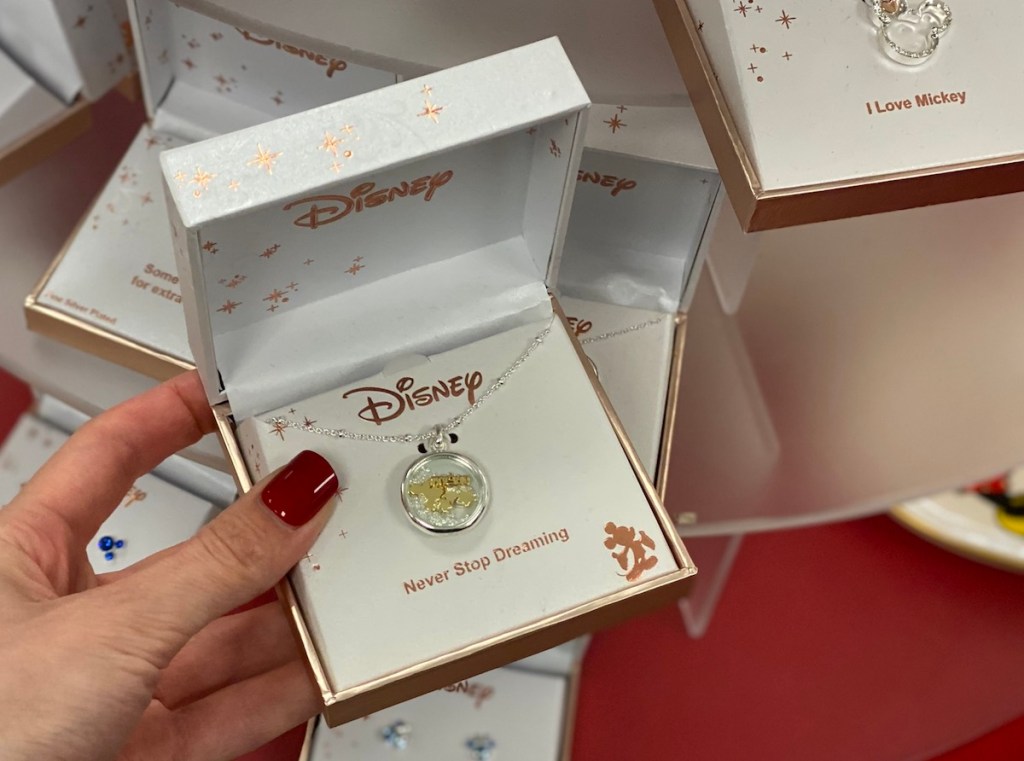 hand holding a jewelry box with a Disney necklace in it