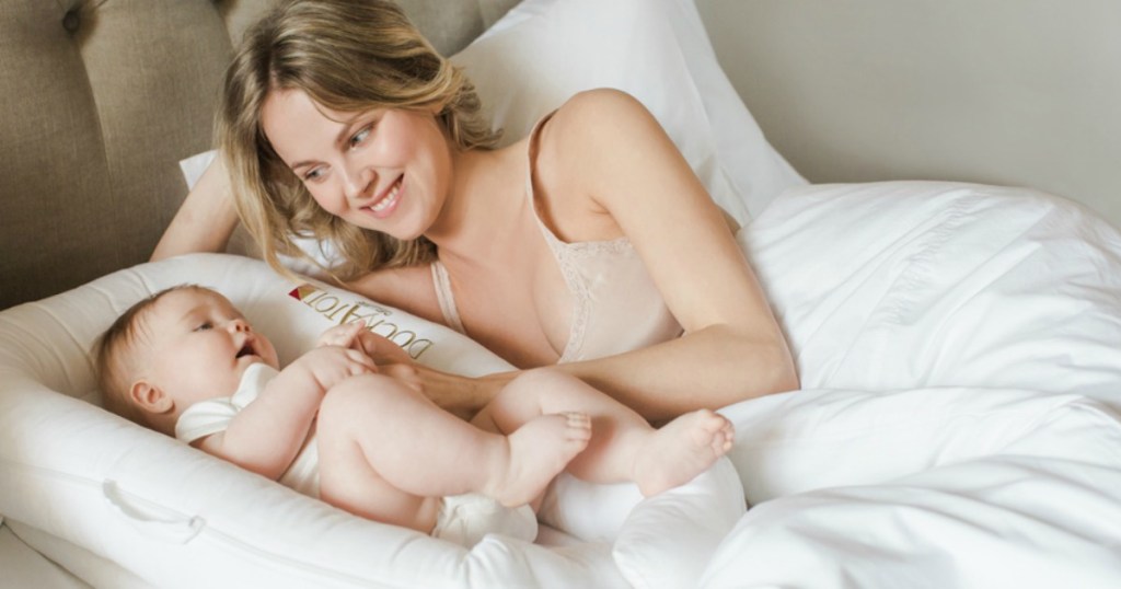 woman looking at a baby laying on a bed