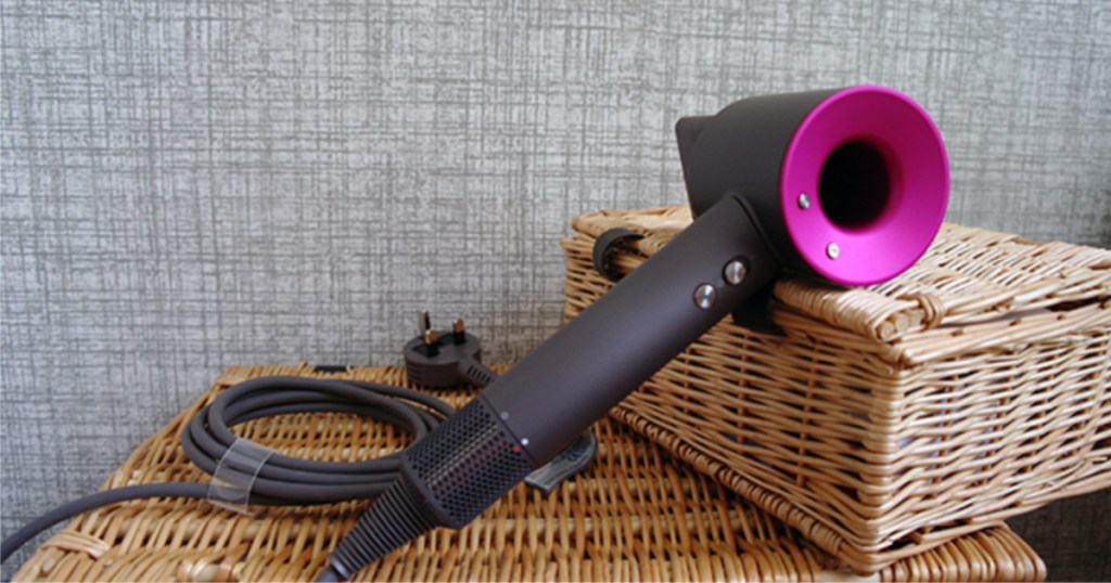 Pink Dyson Supersonic hair dryer on wicker baskets.