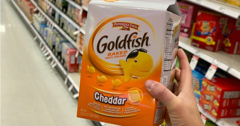 Extra large container of goldfish crackers in hand near shelf in store