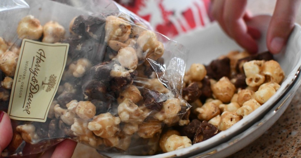 Chocolate covered popcorn with caramel corn being poured into a bowl