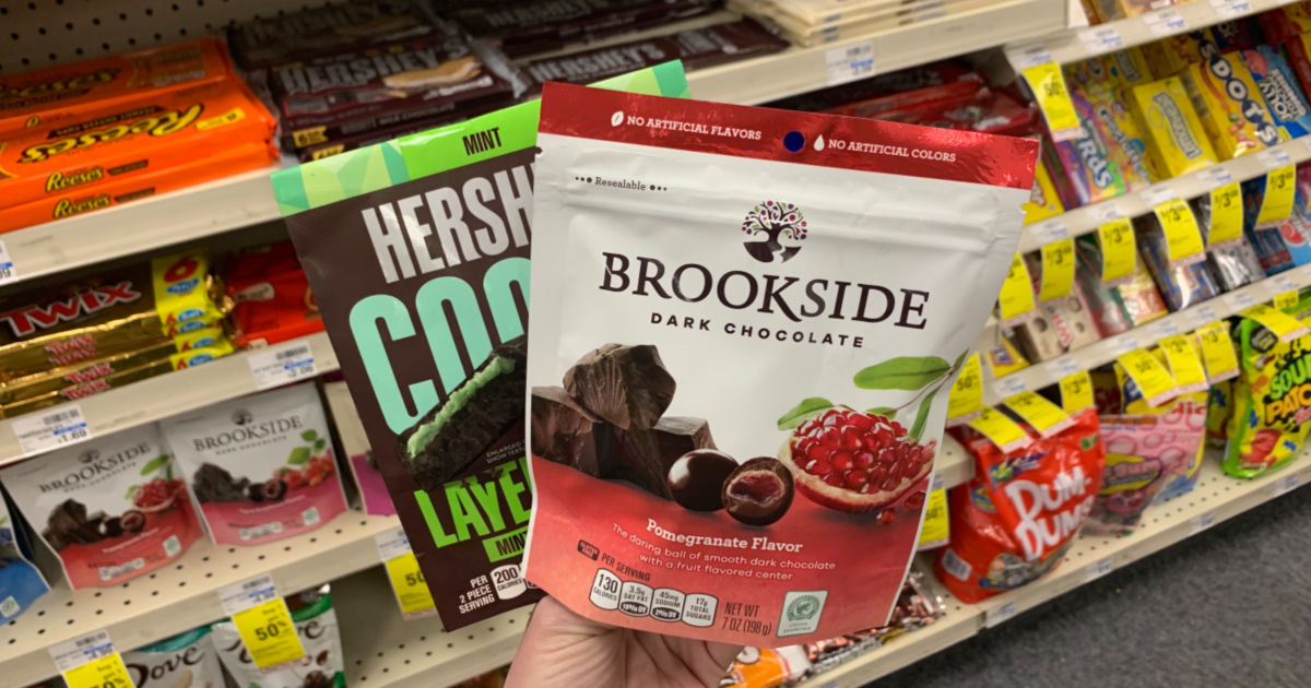 Hand holding chocolate candy in front of shelf 
