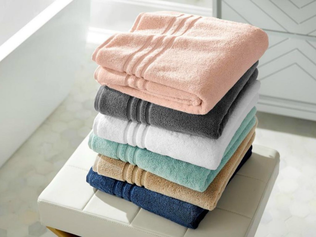 Large stack of folded bath towels in bathroom - in a variety of colors