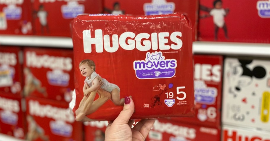 Hand holding up Huggies Diapers