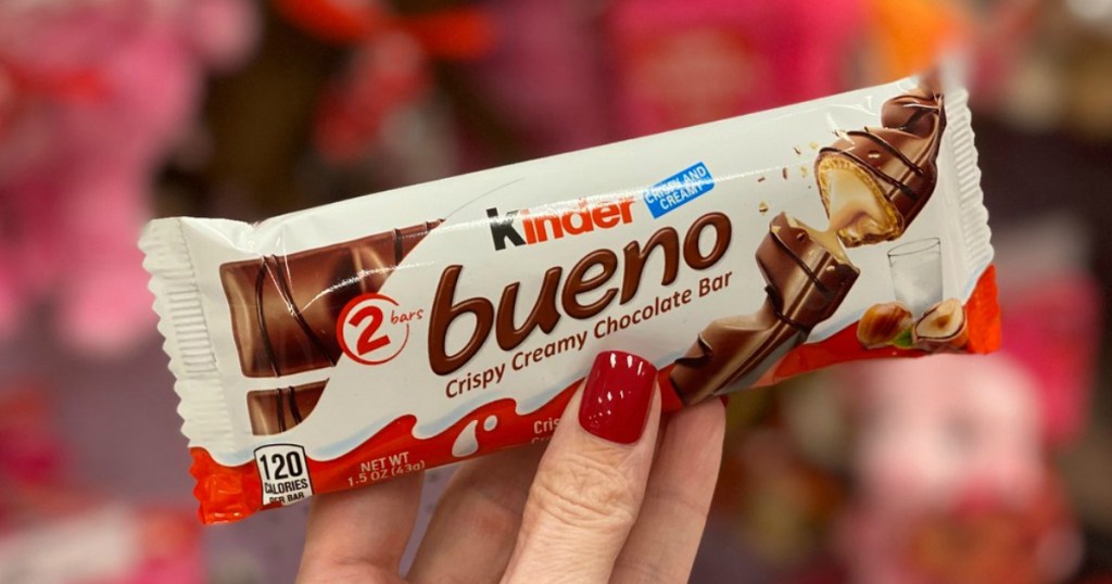 woman with red nails holding a Kinder Bueno candy bar