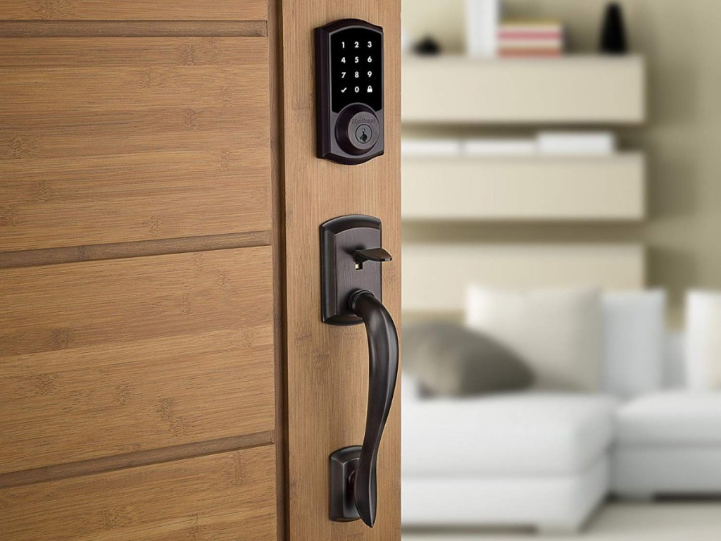 wooden door partially open with black keypad and handle