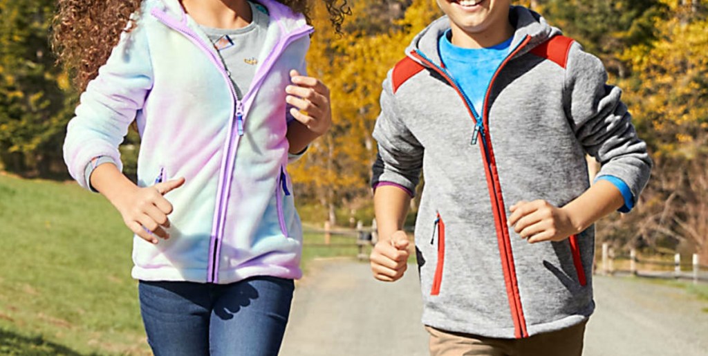Boy and girl running and wearing sweaters, outdoors