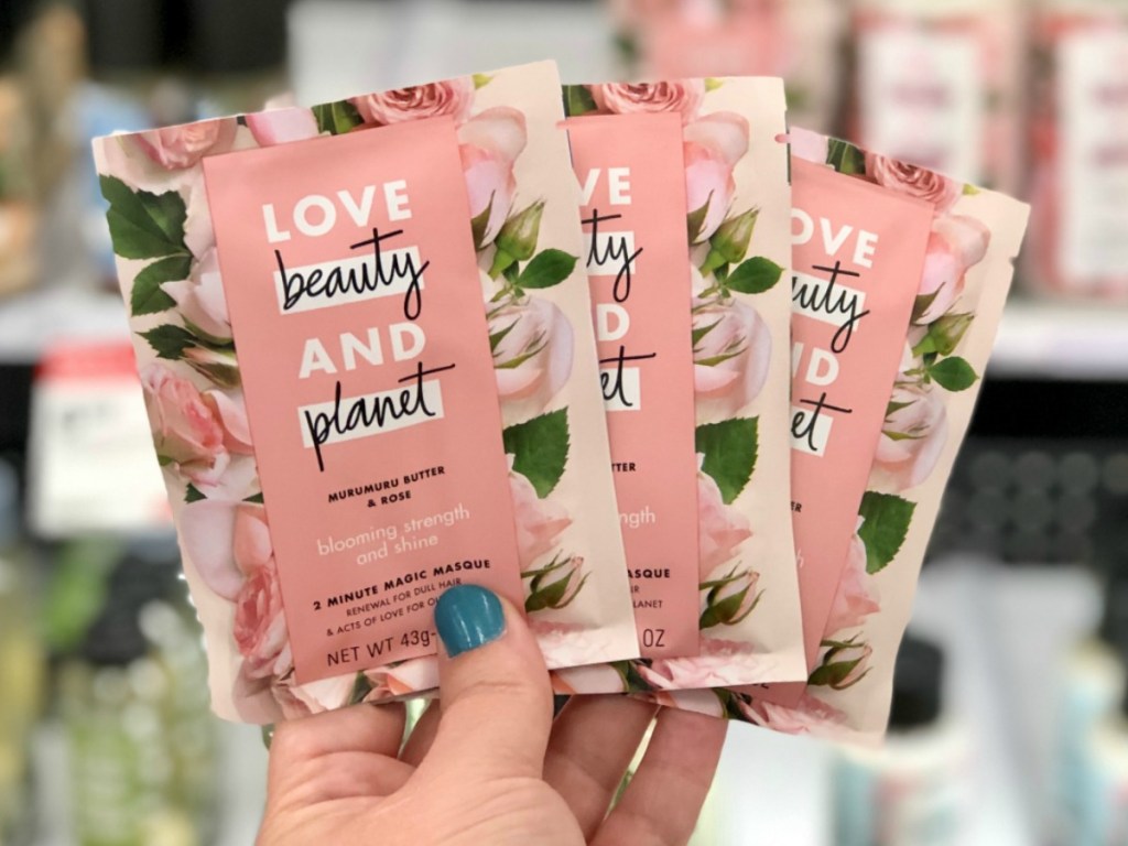 Hand holding three facial masks in packaging in store