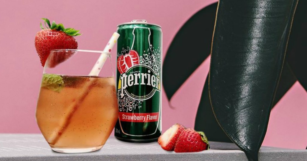 Perrier strawberry can next to a glass or flavored water with a straw, strawberries and a plant