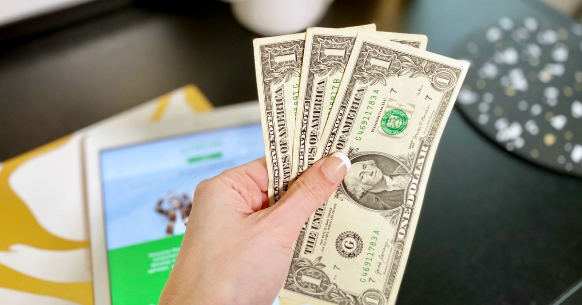 hand holding three dollar bills