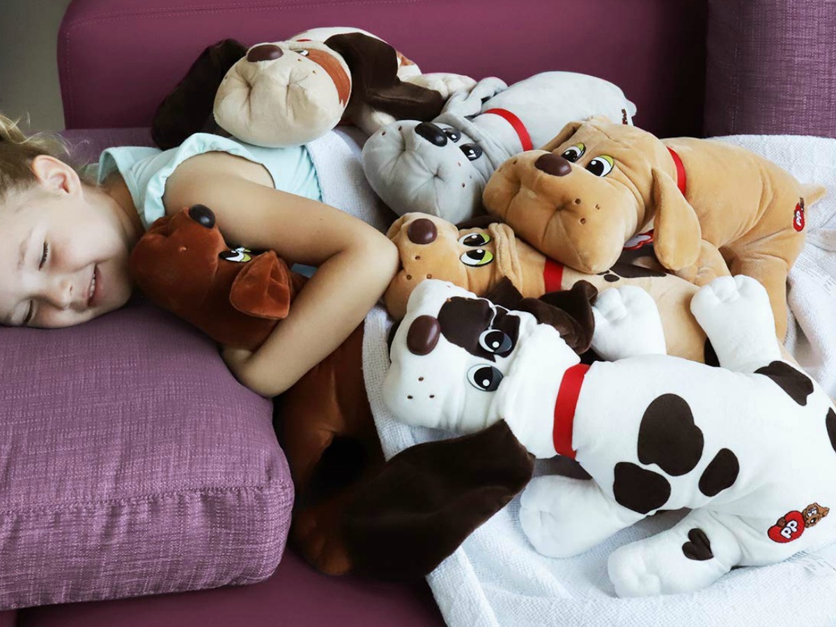 Young girl laying on sofa with a ton of classic sized Pound puppies plush