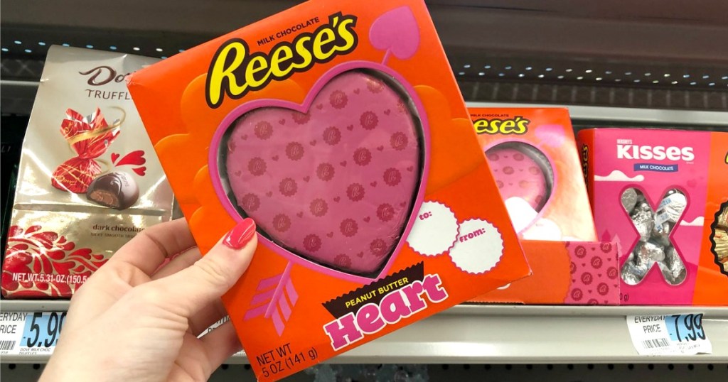 Woman's hand holding a large peanut butter heart in package near in-store clearance display