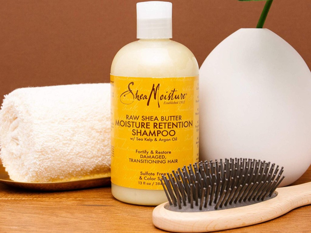 SheaMoisture shampoo next to brush, towel on counter