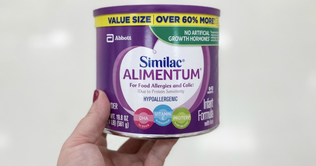 purple canister of infant formula being held by a womans hand
