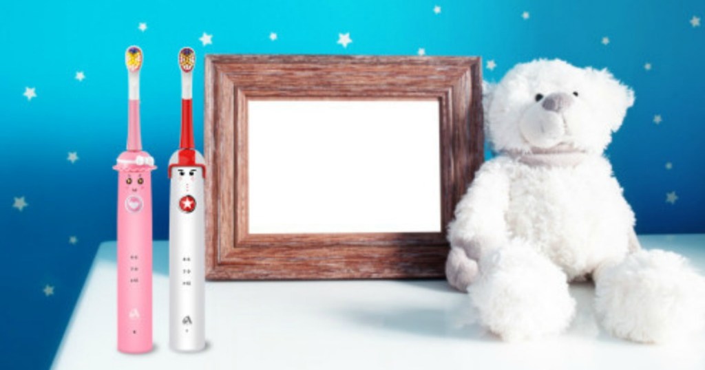 pink and white kids electric toothbrushes on counter near stuffed bear toy