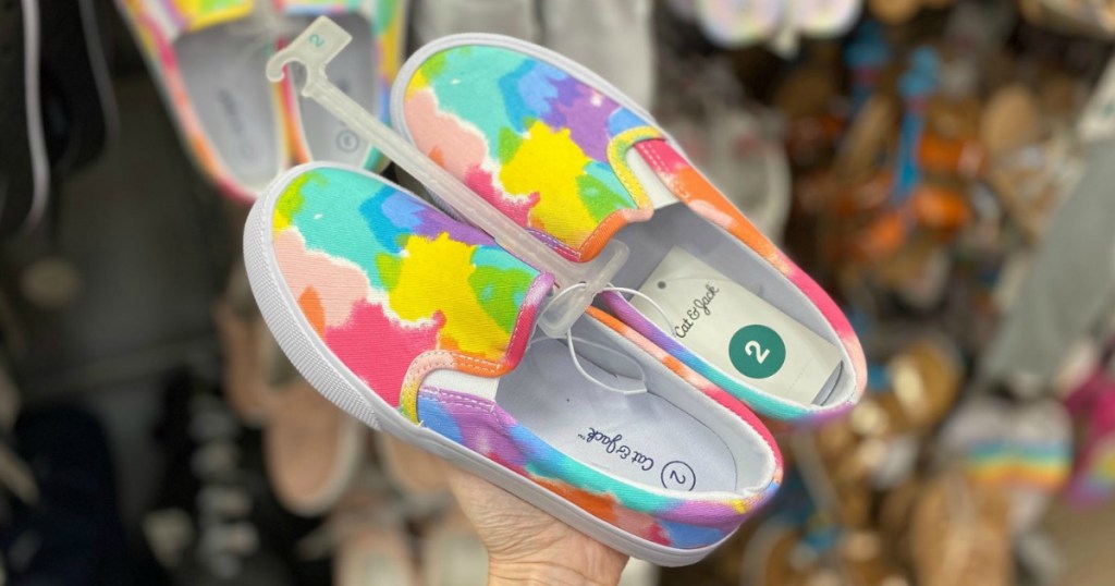 Pair of girls slip on canvas rainbow shoes in hand near in-store display