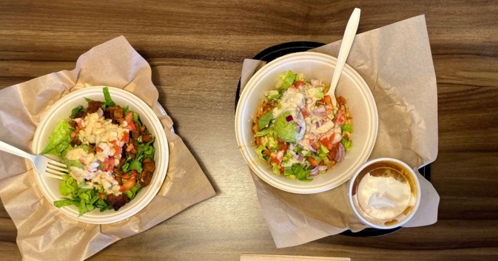 two qdoba meals on table with drink