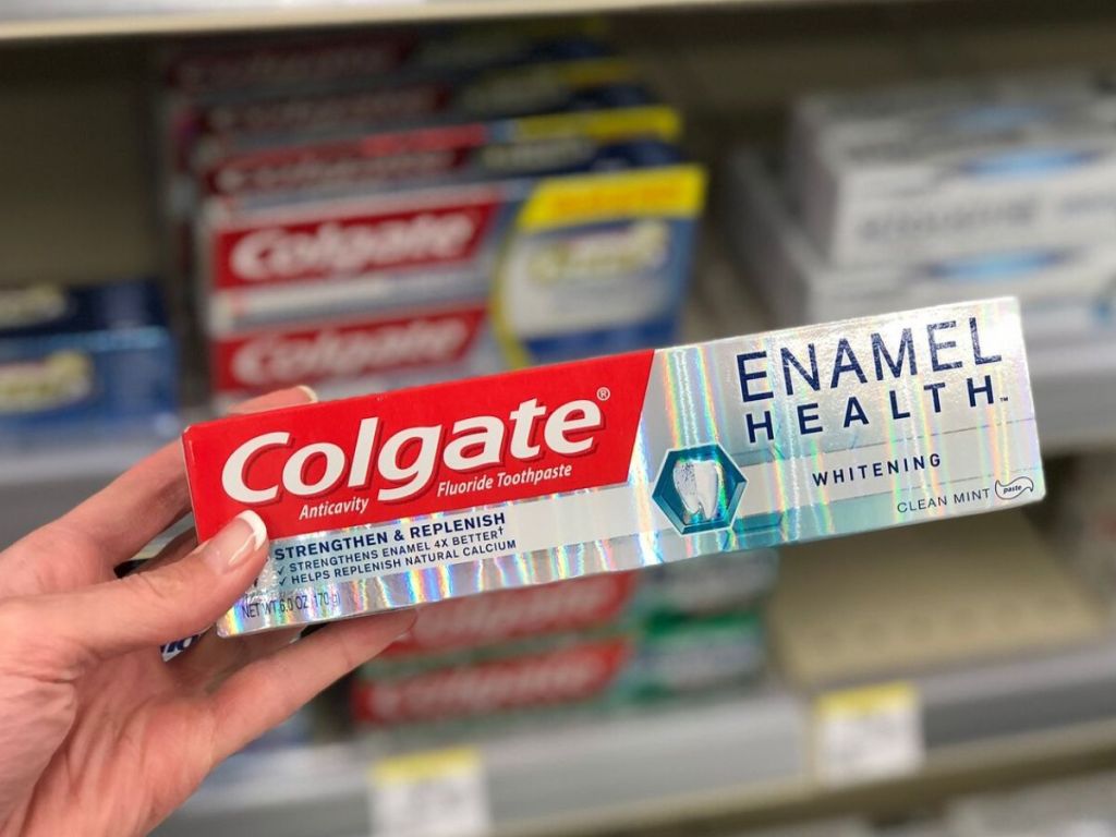 woman's hand holding box of colgate toothpaste