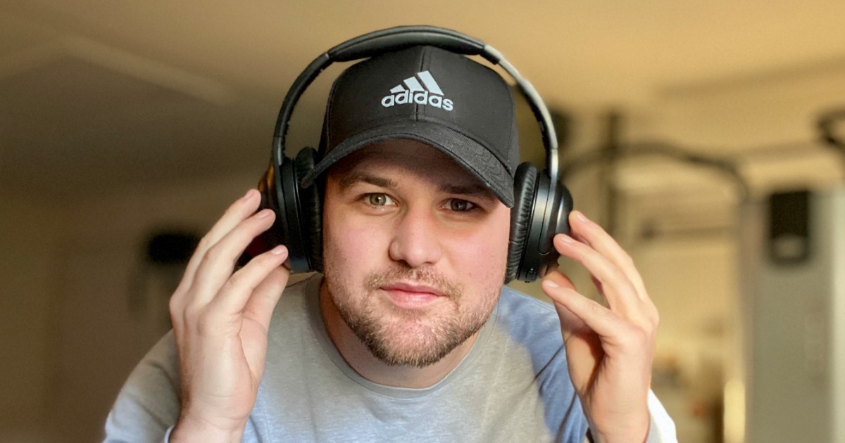 man wearing pair of headphones over a hat looking at the camera