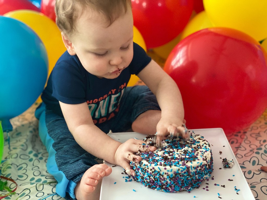 baby boy putting hands into smash cake