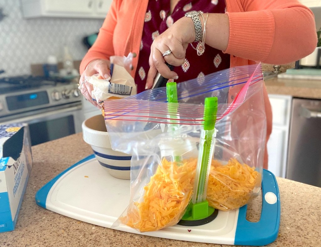 woman prepping food in kitchen with plastic bag in green baggy holder