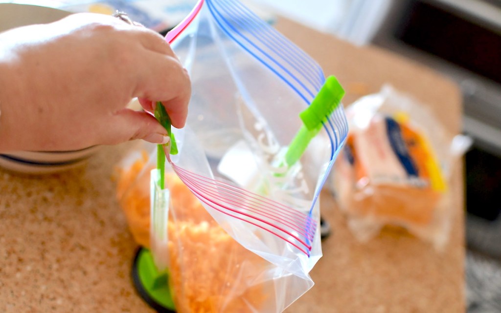 hand holding a ziploc bag open with green and clear stand