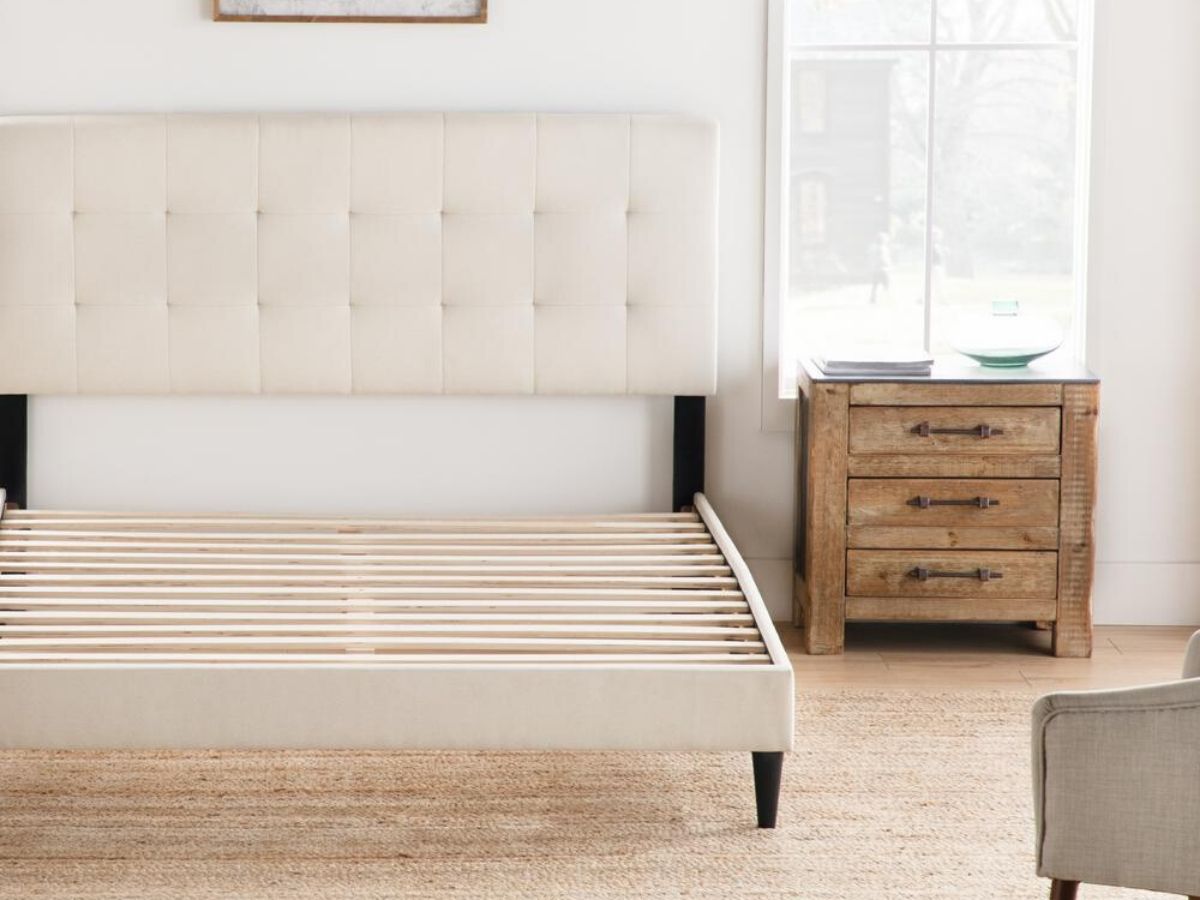 bed frame with upholstered headboard with nightstand on right in front of a window