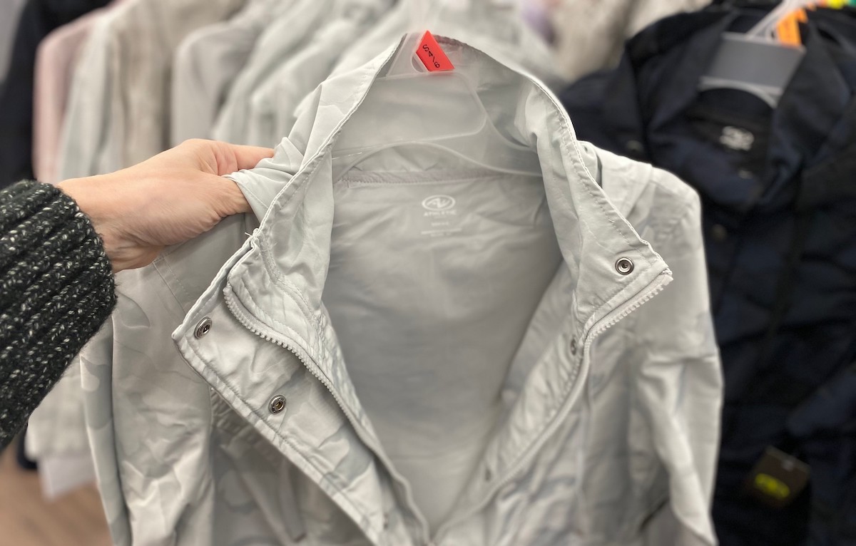 hand holding silver rain jacket jacket on hanger