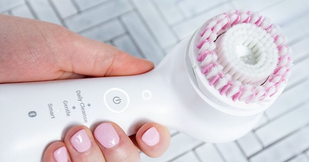 woman's hand holding sonic skincare device with brush head