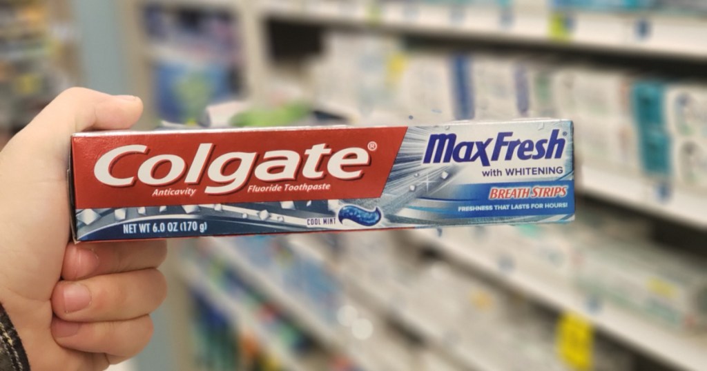 hand holding toothpaste in front of shelf