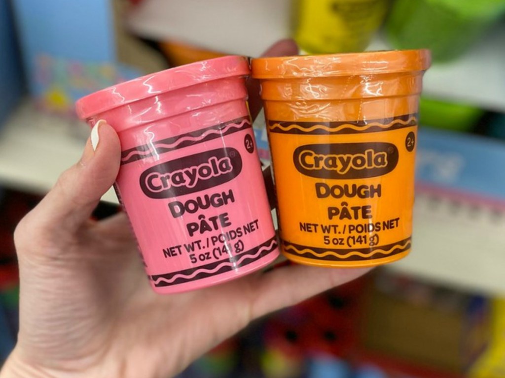 hand holding two packages of play dough