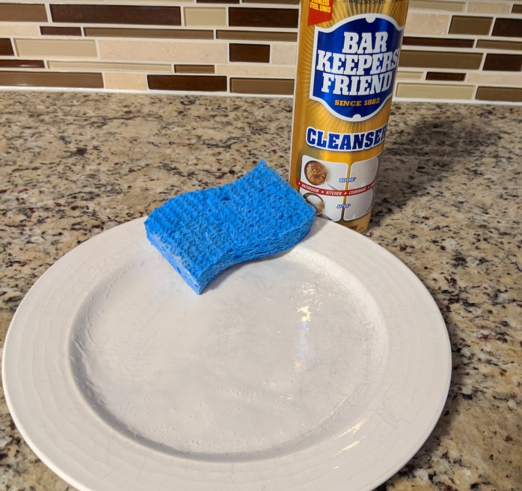white plate with blue sponge on top next to bottle of bar keepers friend
